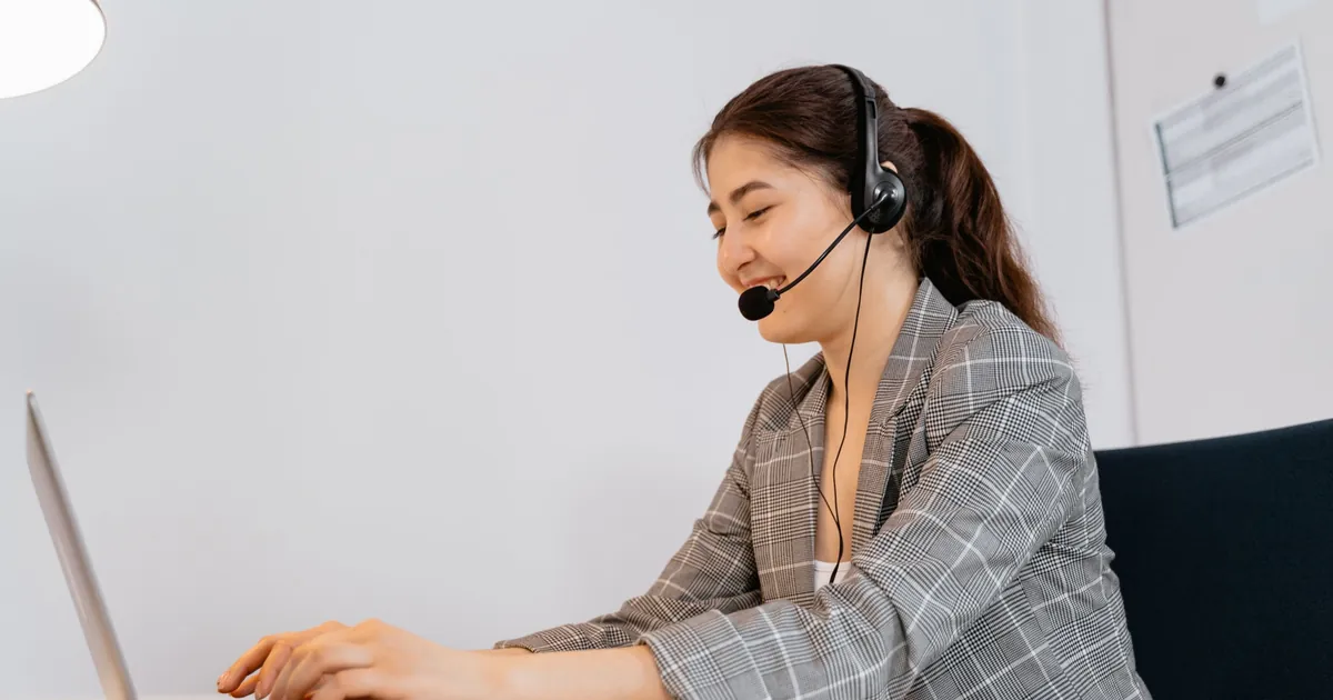 SEO virtual assistant with a headset smiling while working on her laptop